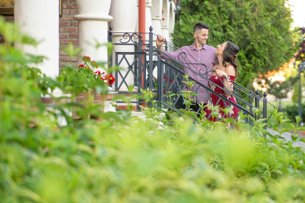 Esküvői fotós által készített jegyesfotózás az Erdőspusztán – Egy szerelmes pár romantikus pillanata egy hangulatos, virágokkal övezett lépcsőnél. Profi esküvői fényképész által megörökített meghitt és természetes páros fotózás az esküvő előtti különleges emlékek megőrzésére.