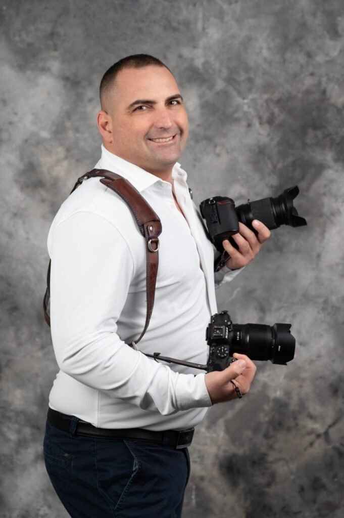 Dobó Imre esküvői fotós fehér ingben, két Nikon fényképezőgéppel a kezében